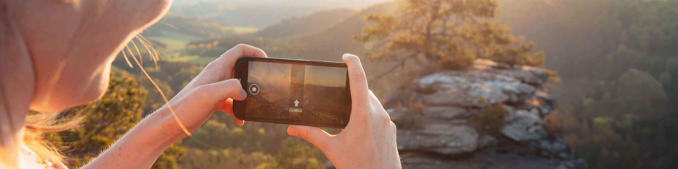 En person tager et snapshot af et smukt landskab med en smartphone.